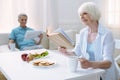 Cheerful nice pensioner reading a book