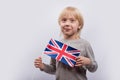 Exciting fair-haired boy holding flag of UK. Learning English for children. Education in United Kingdom