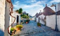 Exciting morning view of strret with trullo trulli - traditional Apulian dry stone hut with a conical roof.