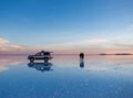 Exciting scenery of spacious Salar de Uyuni with couple and car Royalty Free Stock Photo