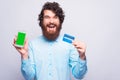 Exciting young man holding credit card and a phone looking at the camera Royalty Free Stock Photo