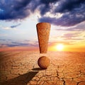 Exclamation mark in the dry landscape with cracked soil at sunset. Royalty Free Stock Photo