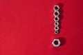 Exclamation mark, made with steel nuts on a red fabric background Royalty Free Stock Photo