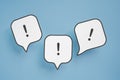 Exclamation mark on real white paper cut speech bubble on blue background Royalty Free Stock Photo