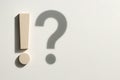 An exclamation mark with the shadow of a question mark on a light wall. Space for text. Royalty Free Stock Photo