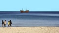 Excursion boat decorated as a pirate ship in front of Boujaafar beach, on which a group of young girls and women are walking