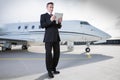 Executive business man in front of corporate jet looking at tabl Royalty Free Stock Photo