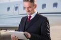 Executive business man in front of corporate jet looking at tabl Royalty Free Stock Photo
