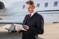 Executive business man in front of corporate jet looking at tabl Royalty Free Stock Photo