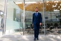 Executive businessman walking. Portrait of ceo near modern office in suit. Happy leader standing in front of company Royalty Free Stock Photo