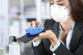 Executive hands with mask disinfecting phone with sanitizer