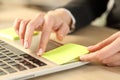 Executive hands sticking post note over laptop