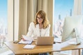 Executive mid aged professional woman sitting at desk in a modern office and working Royalty Free Stock Photo