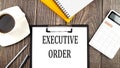 EXECUTIVE ORDER text on paper with coffee, calculator and notebook. Business concept