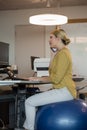 Executive talking on mobile phone while sitting on exercise ball