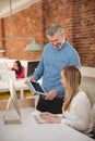 Executives discussing over digital tablet at desk Royalty Free Stock Photo