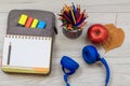 Exercise book on bag-pencil case with color felt pens and marker, headphones, apple and color pencils on grey background Royalty Free Stock Photo