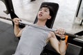 Exercise concept The man who wears grey t-shirt laying himself on weight machine and trying to lift the weight up from his chest