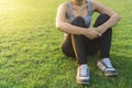 Exercise and healthy concept, Young asian woman runner sitting on green grass to relax after jogging in the park at morning time, Royalty Free Stock Photo