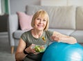 Exercise and healthy diet concept. Senior woman with fitball eating fresh vegetable salad at home Royalty Free Stock Photo