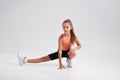 Exercise more. Flexible cute little girl child looking at camera while stretching her body isolated on a white