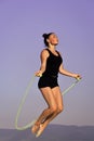 Exercises with a skipping rope. Workout of girl on blue sky background. Royalty Free Stock Photo