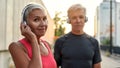 Exercising with music. Portrait of beautiful and positive middle-aged couple in headphones looking at camera with smile