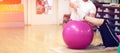 Exercising with personal trainer on large stability ball in studio fitness back