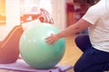 Exercising with personal trainer on large stability ball in studio fitness back