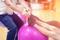 Exercising with personal trainer on large stability ball in studio fitness back