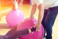 Exercising with personal trainer on large stability ball in studio fitness back