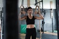 Exercising woman holding gymnast rings. Female taking rest after intense dip ring workout at gym Royalty Free Stock Photo