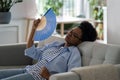 Exhausted African American woman housewife lies on sofa stressed because of high temperature Royalty Free Stock Photo