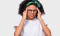 Exhausted African American young woman touching her head with closed eyes wearing white t-shirt,  green headband and eyewear. Afro Royalty Free Stock Photo