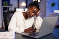 Exhausted african freelancer resting head on hand in front of laptop