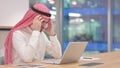 Exhausted Arab Businessman with Laptop having Headache in Office