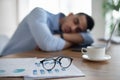 Exhausted Arab businessman sleeping on his office desk, tired of overworking, selective focus on documents and glasses