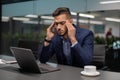 Exhausted arab guy entrepreneur suffering from headache, office interior