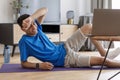 Exhausted arab man near laptop watching training video online, lying on fitness mat tired of exercising at home