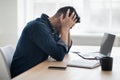 Exhausted arab man sitting in front of laptop, office interior