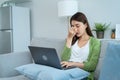 Exhausted Asian business woman hurt eye while using laptop computer. Young girl office worker sit on sofa feel visual fatigue and