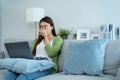 Exhausted Asian business woman hurt eye while using laptop computer. Young girl office worker sit on sofa feel visual fatigue and