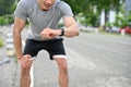 Exhausted asian male athlete hands on knee, checking his heart rate on smartwatch