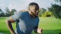 Exhausted athlete running fast in park. Man breathing during marathon outdoors