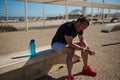 Exhausted athletic man checking his smart wrist watch, resting after bodyweight training in outdoor urban sports ground