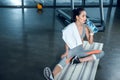 exhausted athletic woman drinking water while sitting on yoga mat