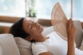 Exhausted biracial woman wave with hand fan suffering from heatstroke