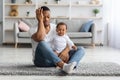 Exhausted Black Father Sitting With Crying Newborn Baby On Floor At Home