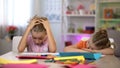 Exhausted boy and girl sitting at table, tired after drawing, falling asleep Royalty Free Stock Photo