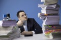 Exhausted businessman looks at high pile of documents. too much of paperwork Royalty Free Stock Photo